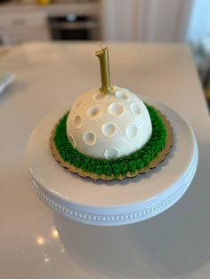 a white cake with green grass and a golf ball on it's top that has the number one on it