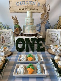 a table topped with cakes and cupcakes next to a sign that says first birthday