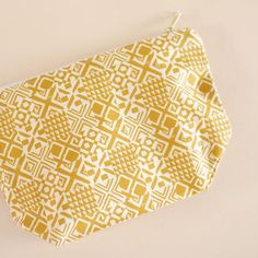 a yellow and white patterned pouch hanging on a wall next to a pair of scissors