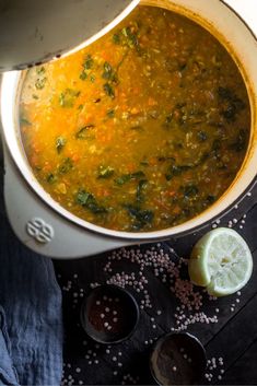 a pot filled with soup sitting on top of a table next to some lemons