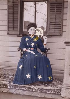 an old photo of a woman sitting in a chair with stars on her dress and holding a wrench