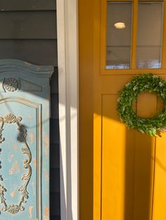 a blue and yellow door with a wreath on the side of it next to an orange front door