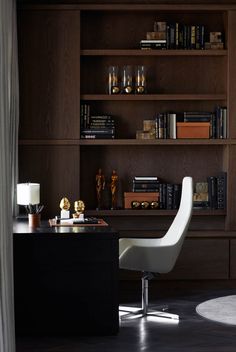 a desk with a chair and bookshelf in the background