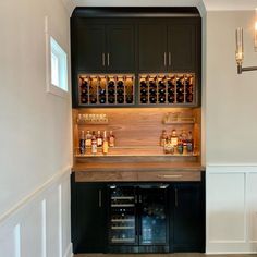 a wine cellar in the corner of a room with black cabinetry and wood flooring