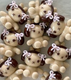 there are many brown and white teddy bears with pink bows on their heads, all in the same pattern