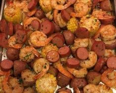 a tray filled with shrimp, sausage and corn on the cob