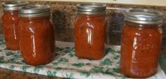 three jars filled with red sauce sitting on top of a counter