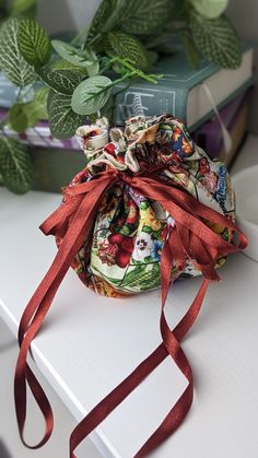 a bag with red ribbon tied around it sitting on a table next to some books