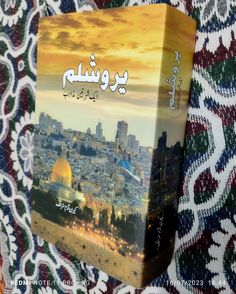 the book is sitting on top of a colorful blanket in front of a cityscape