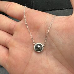 A heavily peppered rose-cut diamond sits stationary on a dainty sterling silver chain. The bezel is made of sterling silver with a sandblasted finish. The chain is 16 inches in length, and the pendant measures just over 1/3 of inch. The diamond is 1.38ct. Handmade in our Arvada studio. Minimalist Sterling Silver Necklace With Rose Cut Diamonds, Silver Pendant Necklace With Single Cut Diamonds, Sterling Silver Diamond Necklace For Gift, Silver Necklace With Single Cut Diamonds For Everyday, Everyday Silver Necklace With Single Cut Diamonds, Silver Rose Cut Diamond Round Pendant Necklace, Silver Necklace With Rose Cut Diamond Round Pendant, Sterling Silver Necklace With Bezel Setting For Everyday, Minimalist Solitaire Necklace With Rose Cut Diamonds