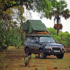 an suv parked in the middle of a field with a tent on it's roof