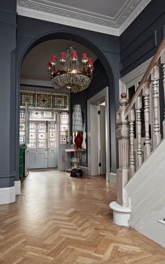 an entryway with chandelier and wooden floors in a home that is painted blue