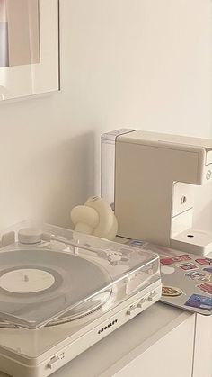 a record player sitting on top of a white counter next to a mirror and other items