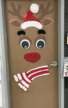 a door decorated to look like a reindeer with a santa hat and scarf on it