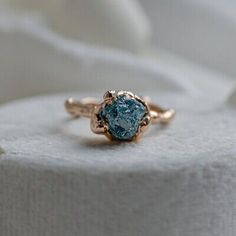 a gold ring with a blue topazte stone in the center on a white surface