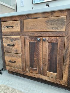 a bathroom vanity made out of wood with metal handles and knobs on the doors