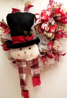 a christmas wreath with a snowman wearing a top hat and scarf hanging on the wall