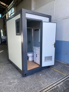 a portable toilet sits in the middle of a parking lot next to a building with blue walls