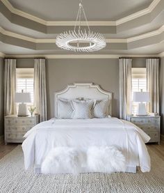 a white bed sitting in a bedroom next to two lamps on either side of the bed