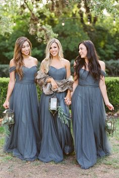 three beautiful women in long dresses standing next to each other