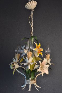 a chandelier with flowers hanging from it's sides and two lights on each side