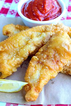 fried fish with lemon wedges and ketchup on the side