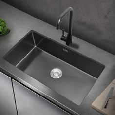 a stainless steel kitchen sink with black faucet and grey countertop next to vegetables