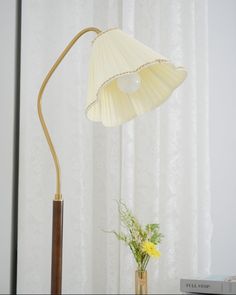 a table lamp sitting on top of a desk next to a vase with flowers