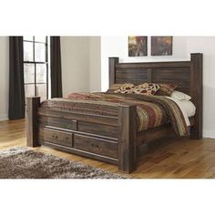 a bed with wooden headboard and foot board on hardwood flooring next to window