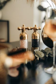 two golden faucets sitting on top of a table next to a glass of wine