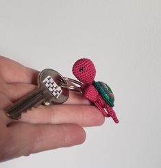 a hand holding a key chain with a small toy on it