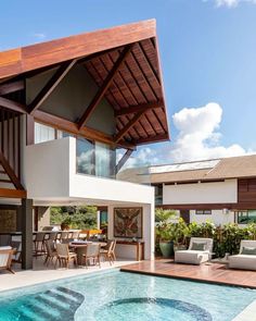 an outdoor living area with a pool and dining table next to the swimming pool is surrounded by greenery