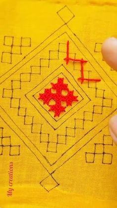 someone is stitching the design on a yellow piece of cloth with red thread and scissors