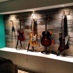 guitars are lined up on a shelf in front of a wood paneled wall with lights