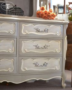 an old dresser is painted white and has flowers on top