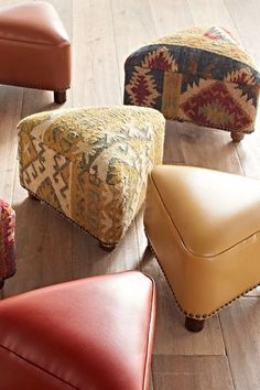 four different colored foot stools sitting on top of a wooden floor next to each other