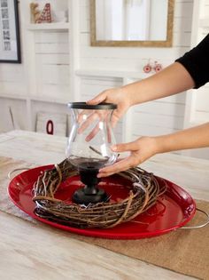 a person is pouring water into a coffee pot on a red plate with twine around it