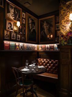 a table with two glasses on it in front of some framed movies and pictures above