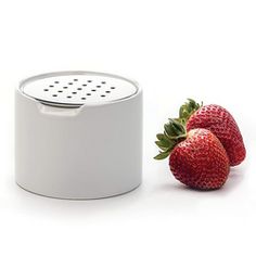 two strawberries sitting next to a white container