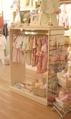 a person standing in front of a clothing rack with baby clothes on top of it