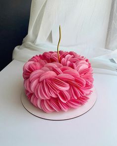 a pink cake sitting on top of a white table