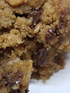 a close up of a piece of food on a white plate with chocolate chips and crumbs