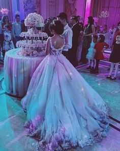 a woman in a wedding dress standing next to a table with a cake on it