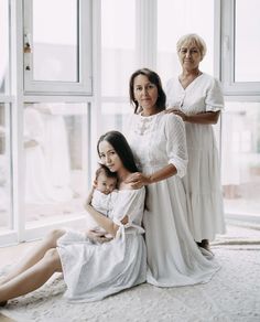 two women and a child are sitting on the floor in front of a large window