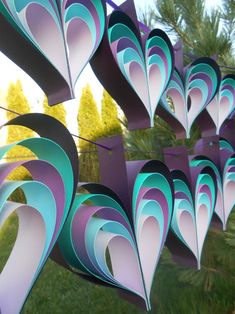 several paper hearts hanging from a string in the shape of heart shapes with trees in the background