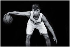 a black and white photo of a man holding a basketball in his right hand while wearing shorts