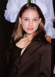 a young woman is posing for the camera with her hand on her neck and wearing a black shirt