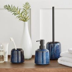 bathroom accessories including soap dispenser, toothbrush holder and towel on wooden table