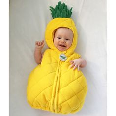 a baby in a pineapple costume laying on its back and smiling at the camera