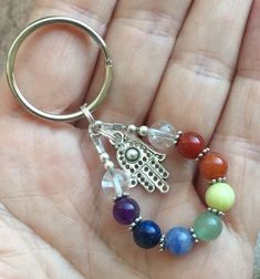 a hand holding a keychain with seven chakrah beads on the end